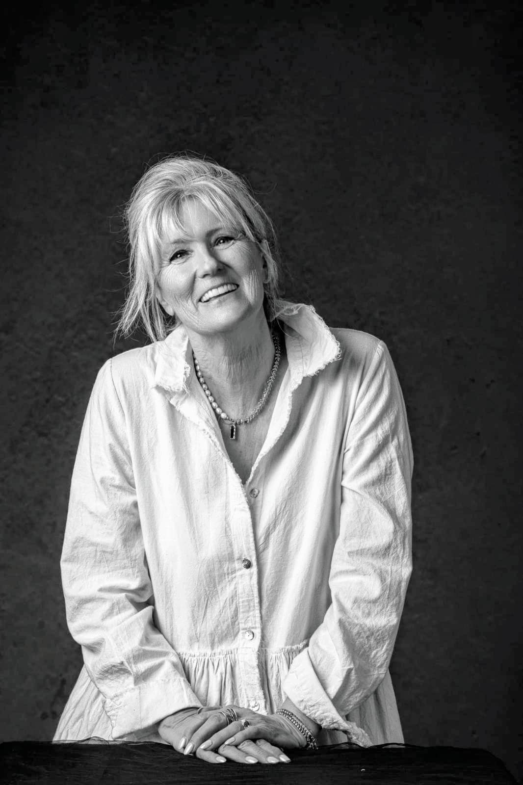 Julie, smiling, in a white linen shirt